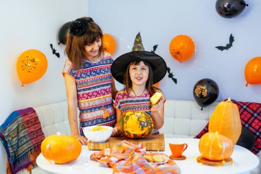 Anne ve kızı Cadılar Bayramı 'nda balkabağının içini temizlerken eğleniyorlar.