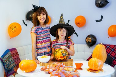 Anne ve kızı Cadılar Bayramı 'nda balkabağının içini temizlerken eğleniyorlar.