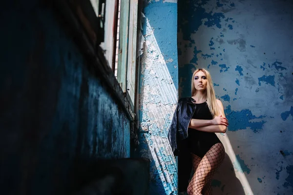 Krásná mladá blondýnka s make-upem v punčocháče a černošky bodysuit pózování na staveništi — Stock fotografie