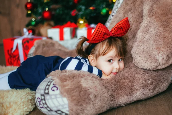 Küçük bir kız Noel Baba 'nın Noel' de verdiği oyuncak ayıyla yatmaktan zevk alıyor. Yeni yıl dekorasyonu — Stok fotoğraf
