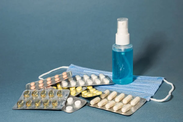 Pandemik önleme. Tıbbi maskeler antiseptik spreyler mavi arka planda vitaminler