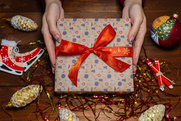 Kadınların elinde Noel hediyesi. Kadın eli yeni yıl hediyesini tutuyor. Yeni yıl dekorasyon arka planı