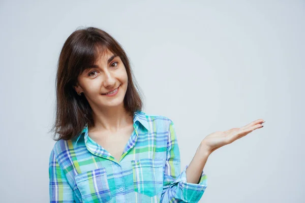 Çekici beyaz kadın avuçlarını açık tutuyor. Gri arka planda bir şey tutuyor.