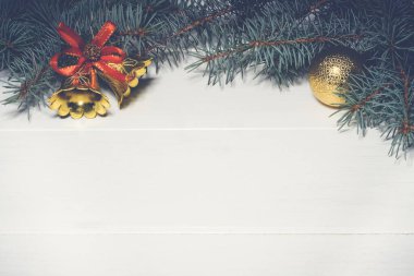 Noel beyaz ahşap arka planı, çam dalları altın toplar, koniler, çanlar. Boşluğu kopyala