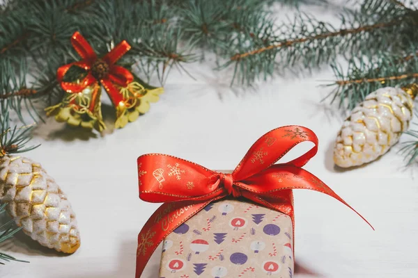 Caja de regalo decorada sobre fondo blanco con campanas de Navidad y ramas de pino y conos — Foto de Stock