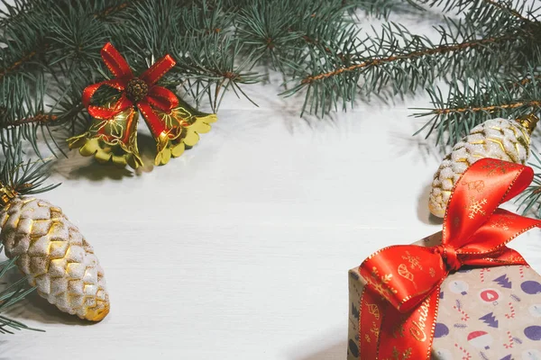 Caja de regalo decorada sobre fondo blanco con campanas de Navidad y ramas de pino y conos — Foto de Stock