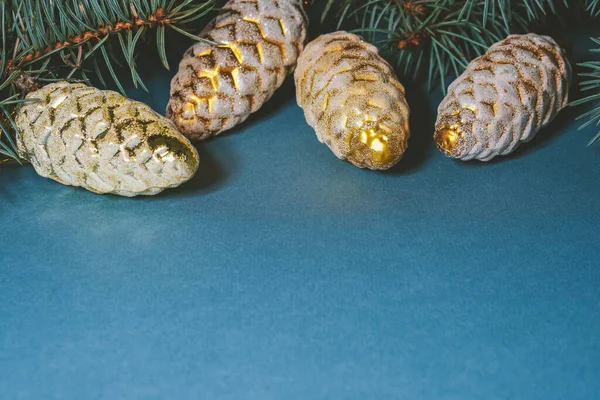 Fondo de Año Nuevo en azul. Ramas de abeto con conos de Navidad de oro. Copia de espacio para texto — Foto de Stock