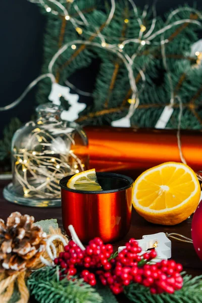 Té de limón en taza de metal naranja y limón en la decoración iluminada de Navidad. Enfoque selectivo — Foto de Stock