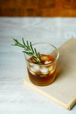 Viski kokteyli, romlu buzlu ve biberiyeli. Beyaz tahta masada alkol kokteyli.