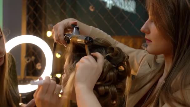 Fodrászat hajsütővas és sminkes csinál frizura és smink, hogy a fiatal nő — Stock videók
