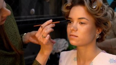 Kaş makyajı mı? Profesyonel makyöz, genç bir kadının kaşlarını düzeltmek için fırça kullanır.