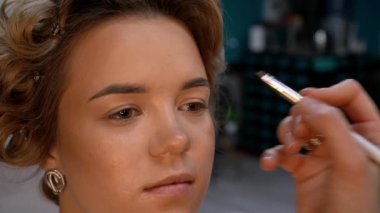 Kaş makyajı mı? Profesyonel makyöz fırçayla genç bir kadının kaşlarını boyuyor. Kapat..