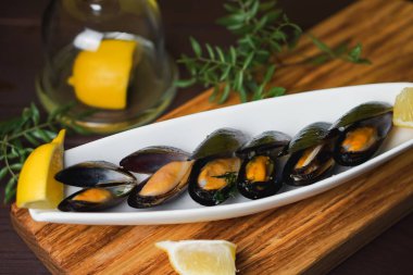 Lavaboda midye ve yukarıdan ahşap masada limon dilimi olan beyaz tabak.