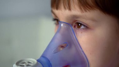 Little girl makes inhalation with medical nebulizer. Close up view