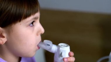Little girl makes inhalation with medical nebulizer at home. Close up view