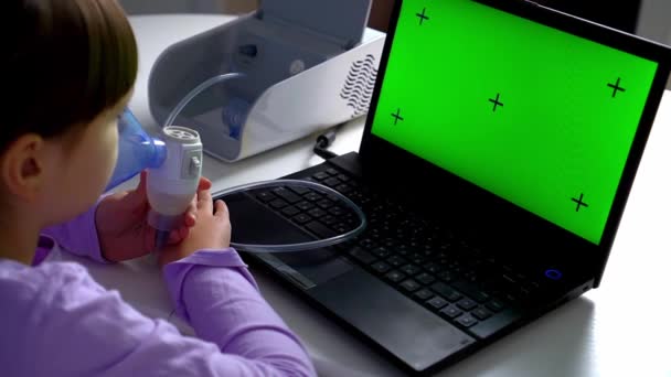 Niña hace inhalación con nebulizador médico mirando a la computadora portátil. Mockup portátil pantalla verde — Vídeos de Stock