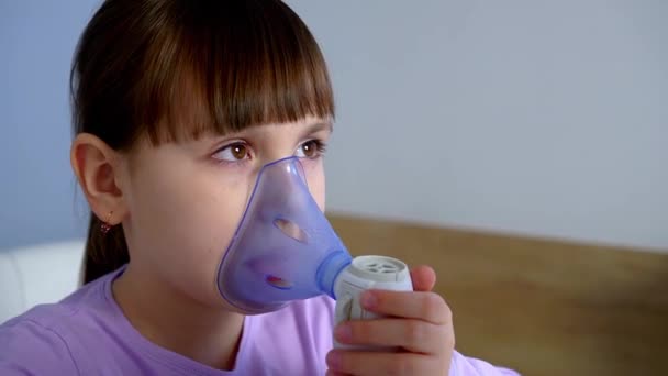 Little girl makes inhalation with medical nebulizer holding mask on face while sitting at table — Vídeos de Stock
