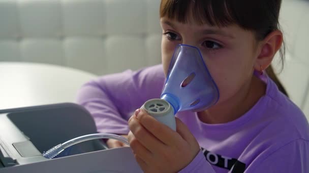 Küçük kız masada otururken tıbbi nebulizatörle solunum yapıyor. — Stok video