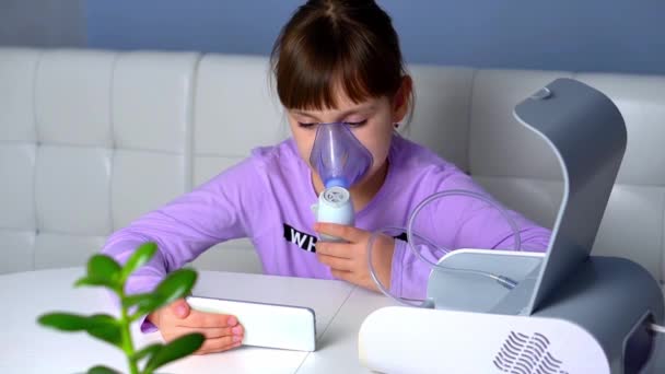 Little girl is sick, makes inhalation with nebulizer through mask on face and looks at phone — Video Stock