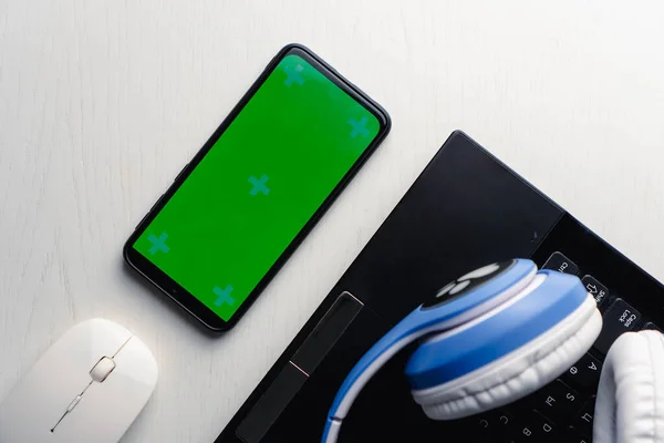 Ακουστικά πληκτρολόγιο laptop και smart pnone με πράσινη οθόνη mockup σε λευκό φούρνο. Έννοια της ζωής με τη μουσική. — Φωτογραφία Αρχείου