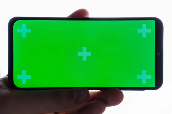 Κοντινό πλάνο του χεριού κρατώντας σύγχρονο smartphone με πράσινη οθόνη αφής που απομονώνονται σε λευκό φόντο — Φωτογραφία Αρχείου