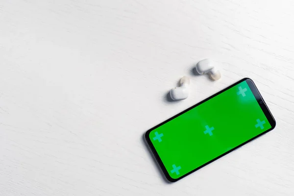 Beyaz arkaplanda izole edilmiş gri ekran model ve beyaz kablosuz kulaklıklı akıllı telefon
