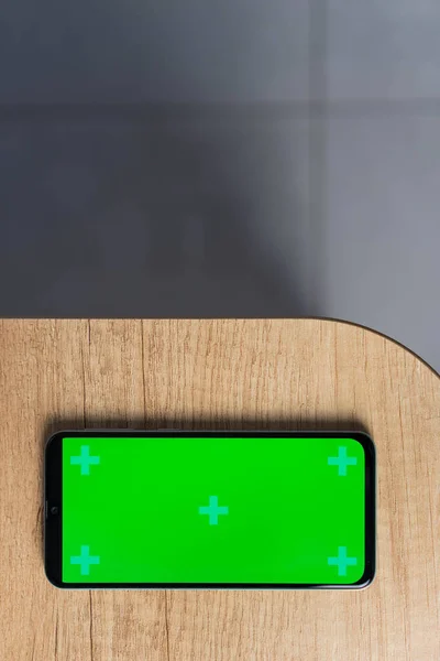 コピースペースと木製の背景に空白の緑の画面のモックアップを持つスマートフォン — ストック写真