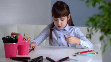 Çocukların yaratıcılığı. Evinde renkli kalemlerle gökkuşağı çizen küçük bir kız çocuğu.
