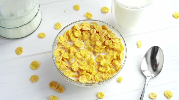 Pouring milk into glass bowl full of crunchy cornflakes cereal in slow motion. Healthy breakfast concept — Stock Video