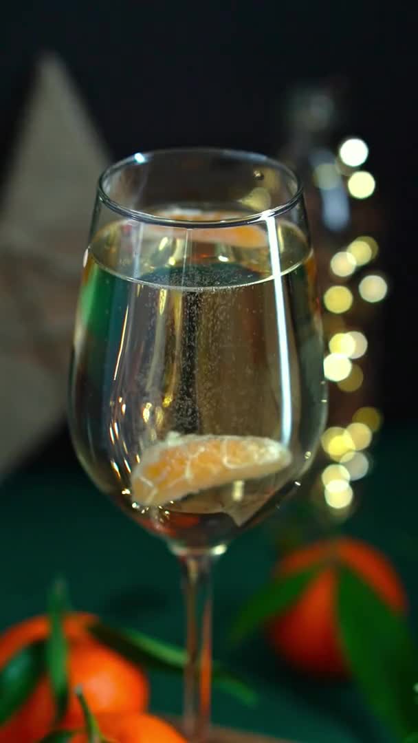 Sparkling wine with tangerine is stired in wineglass on table with mandarins fir brunch and garland — Stock Video