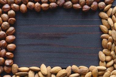 Fındıklı fındıklı ve ahşap masadaki bademli yazı için çerçeve. Sağlıklı organik vejetaryen fındık