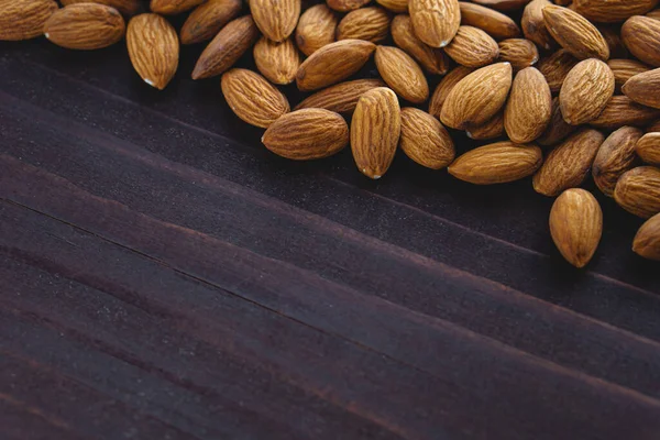 Cerrar las almendras en la mesa de madera oscura. Alimento vegetariano con proteínas orgánicas. Espacio de copia de fondo — Foto de Stock