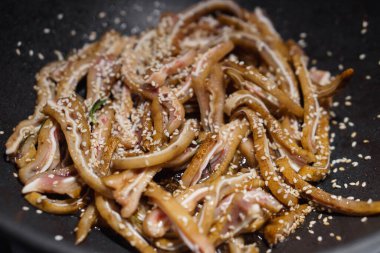 Kızartma tavasına susam tohumu serpiştirilmiş çiğ domuz kulağı üzerine odaklanın. Asya mutfağı menüsü