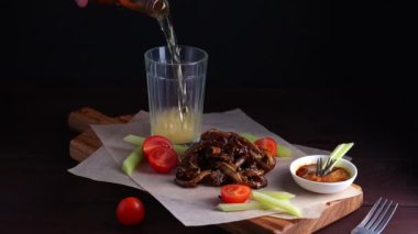 Kızarmış domuz kulağı, domates, kereviz ve sos. Bardağa bira dolduruyorum. Asya mutfağı ızgara menüsü