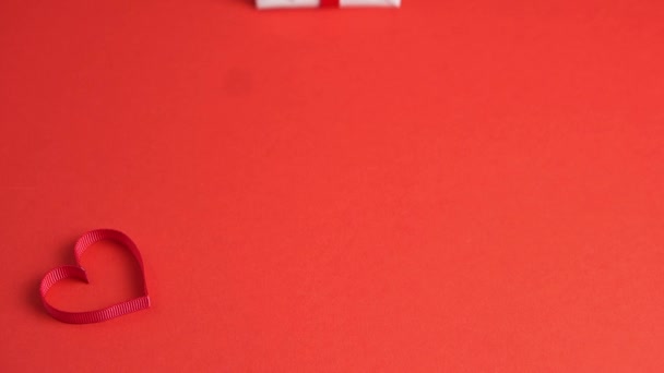 Woman hands put white gift box with red bow on red table decorated with heart. Valentines day — Stock Video