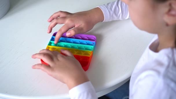 Menina bebê brincando com arco-íris pop it fidget. O conceito de saúde mental popit brinquedo — Vídeo de Stock