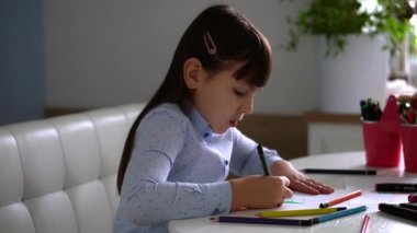 Çocukların yaratıcılığı. Evinde renkli kalemlerle gökkuşağı çizen küçük bir kız çocuğu.