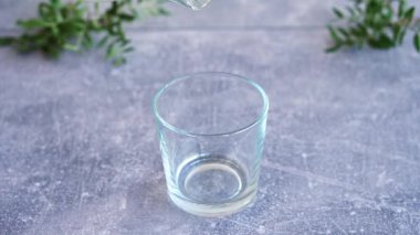 Gri masadaki şeffaf camlara taze içme suyu dökülüyor. Kapat.