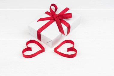 Sevgililer Günü ya da fotokopi çekilen doğum günü konsepti. İki kırmızı kurdele kalp ve beyaz tahta üzerinde hediye kutusu.