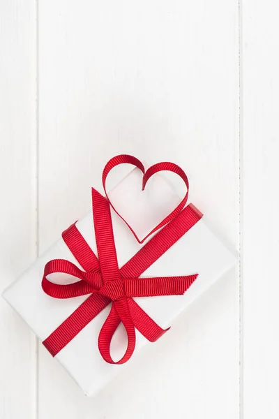 Día de San Valentín o concepto de cumpleaños con espacio para copias. Cinta roja corazón y caja de regalo en madera blanca —  Fotos de Stock