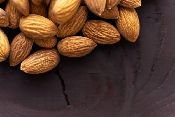 Cerrar las almendras en la mesa de madera oscura. Alimento vegetariano con proteínas orgánicas. Espacio de copia de fondo — Foto de Stock