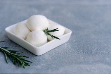 Taze İtalyan beyaz peyniri mozzarella bufalosu beyaz kâse içinde taze biberiye dalıyla servis edilir.