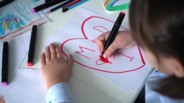 Çocuk pembe kalemlerle kağıt üzerine kalp çizer. Çocukların yaratıcılığı. Sevgililer Günü, mutlu aile.