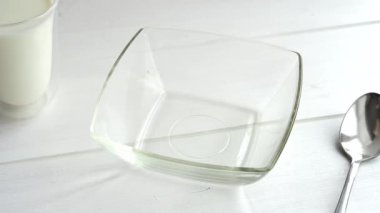 Mısır gevrekleri ahşap masada cam kaseye dökülür. Mısır gevreği ve süt sağlıklı kahvaltı konsepti