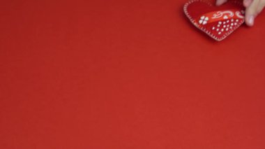 Kız elleri kalbi kırmızı masaya koyar. Çocuk kırmızı kalbi elinde oynatıyor. Sevgililer Günü, Anneler Günü