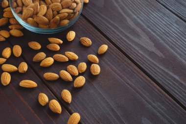 Bademler cam kavanozda ve siyah ahşap masada. Organik sağlıklı protein yiyeceği. Arkaplan kopyalama alanı