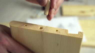 Adam mobilyalara saldırıyor civatalarla vidalama tahtalarına, yakın çekim ellerine. Evde ahşap askı monte ediliyor