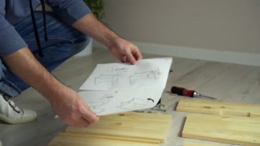 Adam evde mobilya montajı yapıyor. İnsan mobilyaları talimatlara göre monte eder