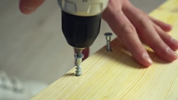Möbler för hemmabruk. Hantverkare driver skruv i träskiva med eldriven skruvmejsel — Stockvideo