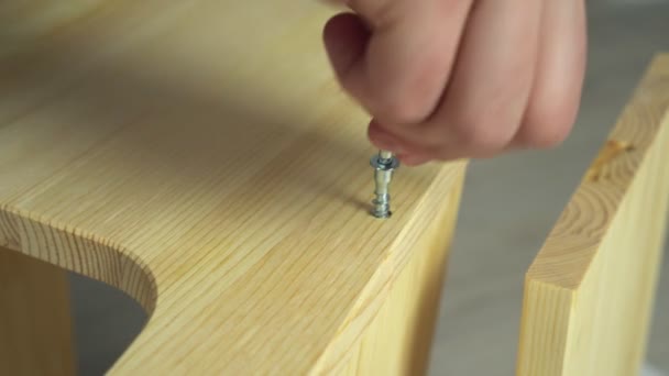 木製の家具を組み立てるクローズアップ手。男は一緒にネジとアレンキーで板を置く — ストック動画
